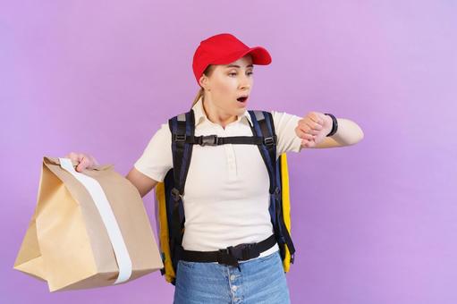 腕時計を見て焦るフードデリバリーの女性 配達,フードデリバリー,デリバリーの写真素材