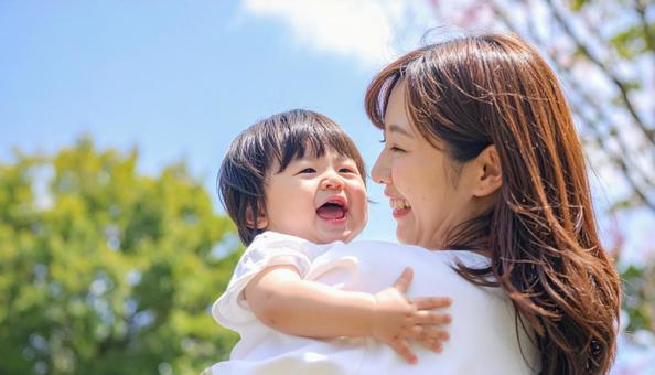 青空の下、子供を抱っこする母親 青空の下、子供を抱っこする母親の写真