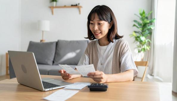 リビングで通帳を笑顔で確認する女性 リビングで通帳を笑顔で確認する女性の写真