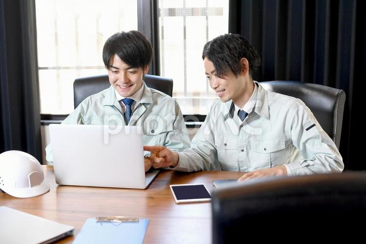 パソコンを操作する作業服を着た男性達 作業服,作業員,打ち合わせの写真素材