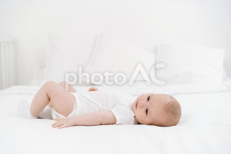 ベッドに寝かされ不安そうな赤ちゃん 赤ちゃん,かわいい,仰向けの写真素材