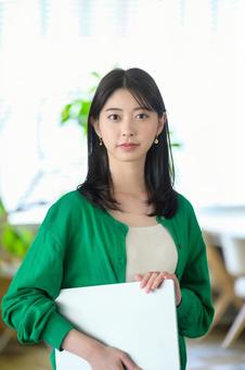パソコンを持つ日本人女性 カメラ目線,日本人,30代の写真素材