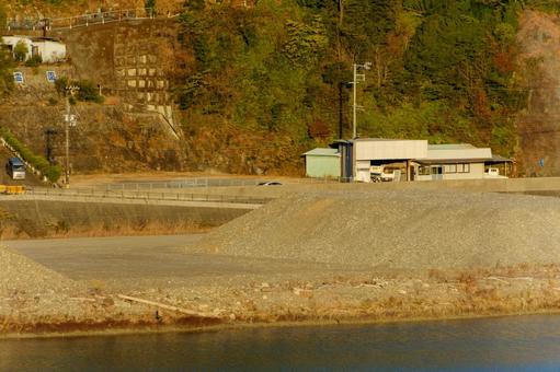 川沿いの資材置き場と小さな建物 川沿いの資材置き場と小さな建物の写真
