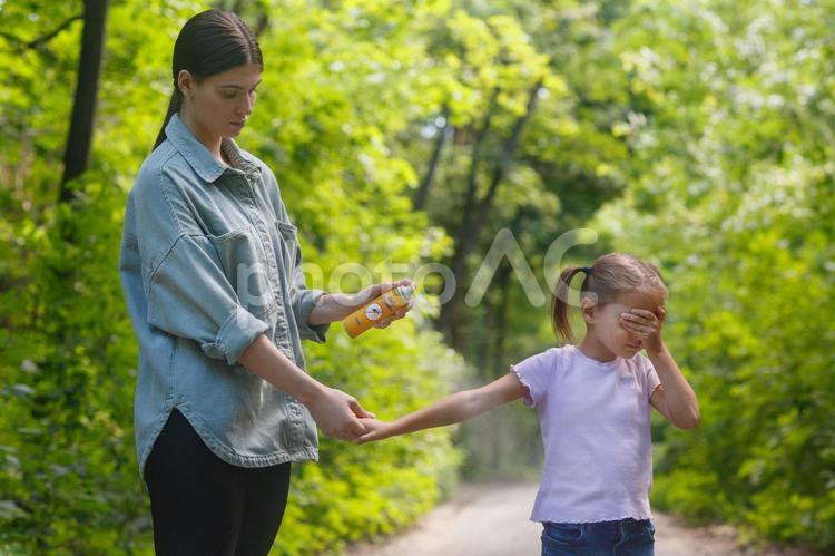 腕に虫除けスプレーをしてもらう女の子 親子,女の子,目を隠すの写真素材