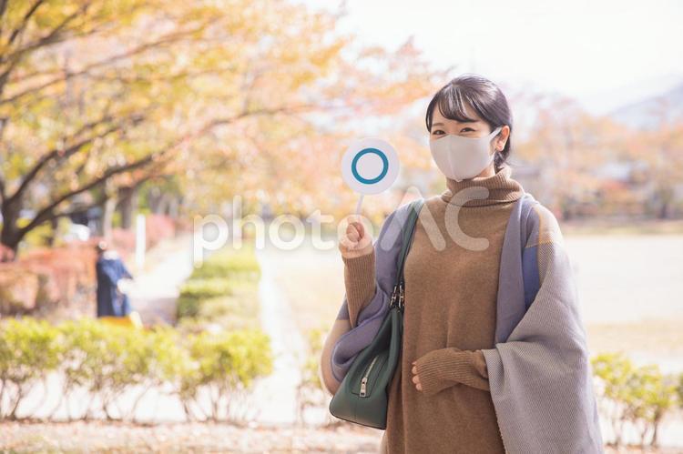 秋の公園でマスクをつけてマルを作る女性 マスク,コロナ対策,感染対策の写真素材