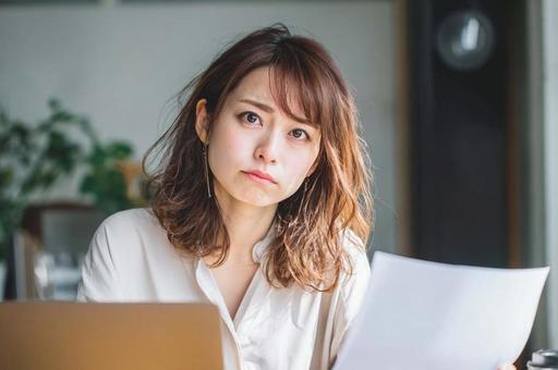資料を見て悩むビジネス女性 資料を見て悩むビジネス女性の写真