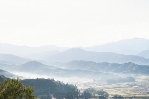 山々に広がる朝霧と淡い光の風景の写真