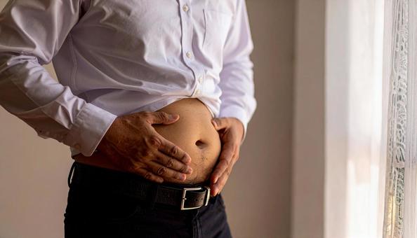 メタボリックなお腹に手を触れる男性 メタボリックなお腹に手を触れる男性の写真