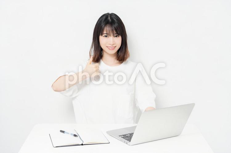 ノートパソコンを使いながら、いいねのジェスチャーをする若い女性 いいね,女性,パソコンの写真素材