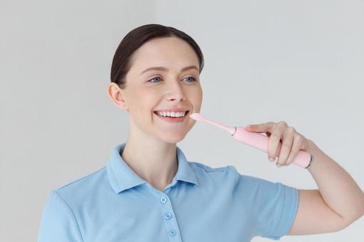 左の方を見て歯磨きする女性 左の方を見て歯磨きする女性の写真