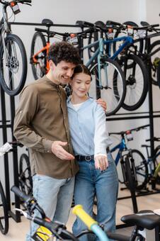 自転車売り場で肩を寄せて立つ若い男女の来店客 男女,カップル,寄り添うの写真素材
