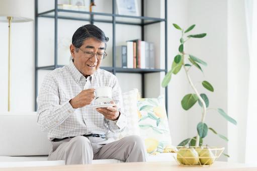 リビングでコーヒーを飲むシニアの男性 リビングでコーヒーを飲むシニアの男性 シニア,コーヒー,男性の写真素材