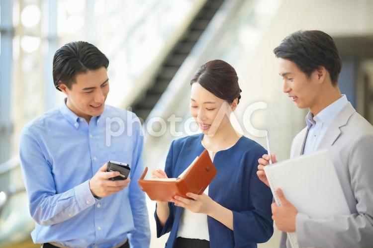手帳を見ながら話をする3人のオフィスワーカー ビジネスマン,ビジネスウーマン,会社員の写真素材