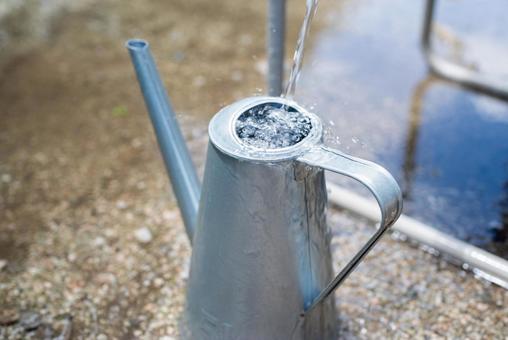 A tin watering can pouring water, JPG