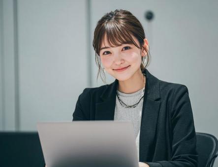 オフィスでパソコンを使う若い女性 オフィスでパソコンを使う若い女性の写真
