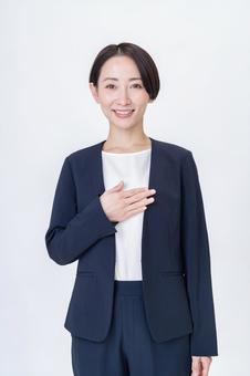 笑顔で胸に手を当てるスーツ姿の女性 ビジネス,女性,案内の写真素材
