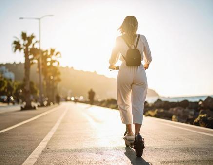 電動キックボードに乗る女性 電動キックボードに乗る女性の写真