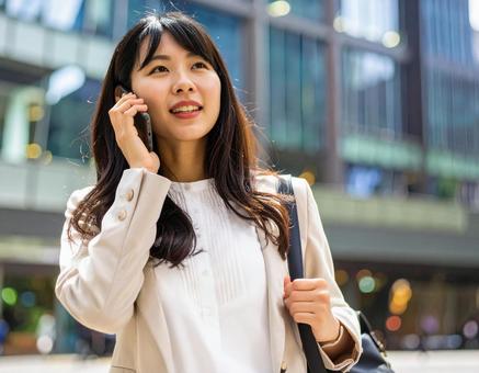 街中で電話をかける女性 街中で電話をかける女性の写真