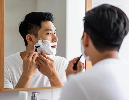 洗面所で髭を剃る男性 洗面所で髭を剃る男性の写真