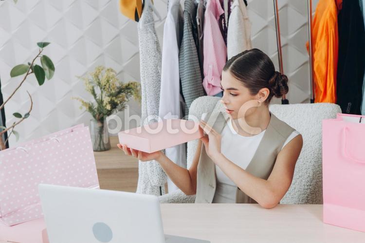 ピンクのギフトボックスを見つめるお団子ヘアの女性 女性,人物,インフルエンサーの写真素材