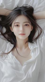 ベッドに横になる笑顔が可愛い日本人の女性の写真