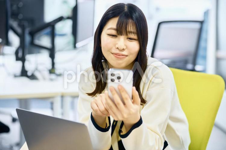 スマホを見る若い女性　オフィス スマホ,デスクワーク,ビジネスウーマンの写真素材
