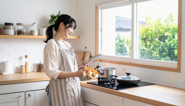 レシピを見ながら料理する日本人の若い女性 レシピを見ながら料理する日本人の若い女性の写真