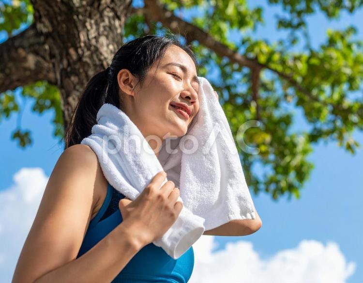 青空の下で汗をふく女性 猛暑,夏,暑いの写真素材
