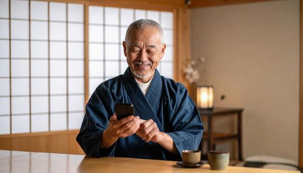 和室でスマホを操作し微笑む和服の高齢男性 和室でスマホを操作し微笑む和服の高齢男性の写真