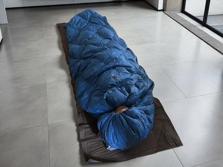 室内で寝袋の中で眠っている人 室内で寝袋の中で眠っている人 寝袋,シュラフ,寝るの写真素材