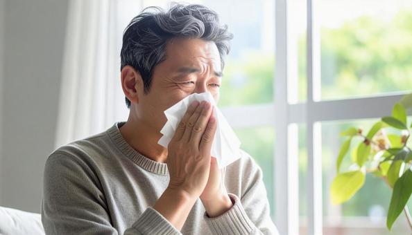 ティッシュで鼻をかむ日本人のミドル男性 ティッシュで鼻をかむ日本人のミドル男性の写真