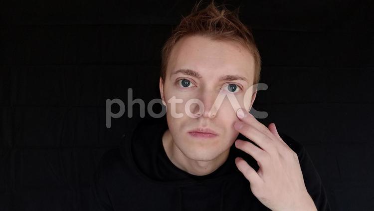「顔に何かがついているかな」と気になっている男　外国人男性　黒バック しわ,しみ,気になるの写真素材