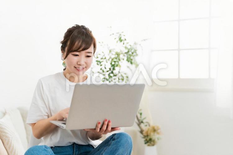 ソファでパソコンを見る日本人女性（笑顔） テレワーク,パソコン,女性の写真素材
