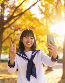 秋の夕暮れにピースする女子学生の笑顔 秋の夕暮れにピースする女子学生の笑顔の写真