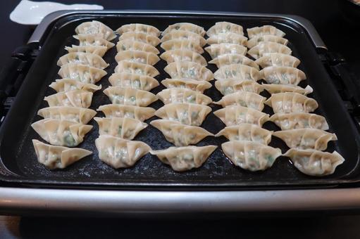 ホットプレートいっぱいの餃子(斜めから) ホットプレートいっぱいの餃子(斜めから)の写真