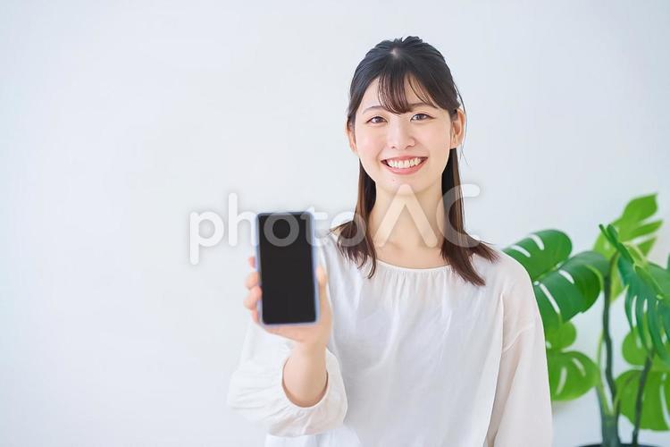 スマートフォンの画面を見せる若い女性 女性,若い,スマートフォンの写真素材