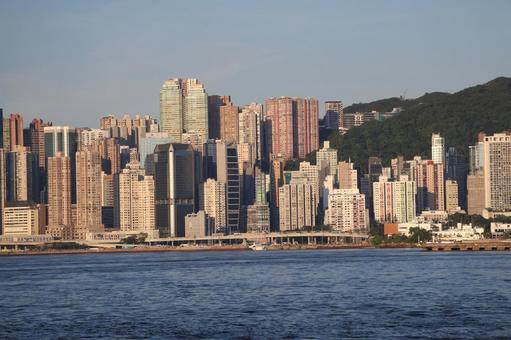 海と高層ビルの街並みと山と空の香港の街の写真