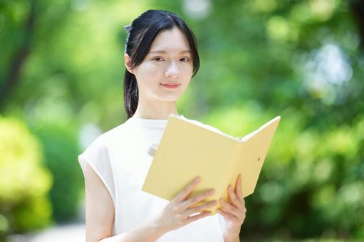 白いノースリーブワンピースの女性が本を見つめるの写真