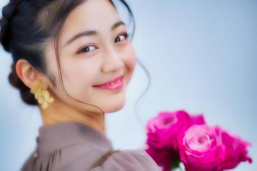 ピンクの花を胸元で抱え優しく微笑む三つ編み女性 女性,日本人,花の写真素材