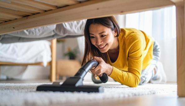 ベッドの下にたまったほこりを掃除する女性 ベッドの下にたまったほこりを掃除する女性の写真