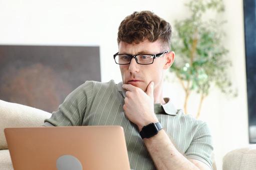 考えながら膝の上のノートパソコンを使う男性 男性,外国人,欧米人の写真素材