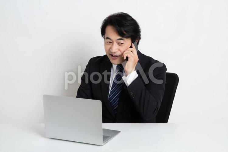 電話をしながら仕事をしている中年のサラリーマン男性 中年,上司,会社員の写真素材