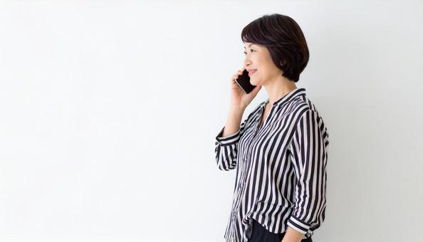 スマホで会話する女性 白背景 スマホで会話する女性 白背景の写真