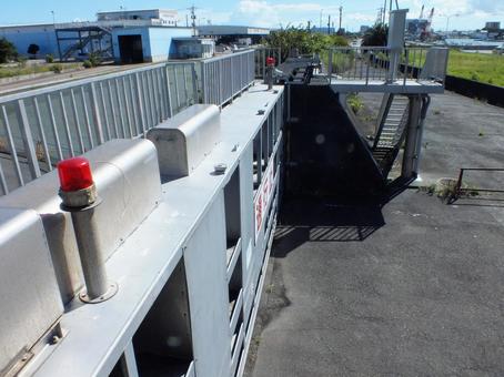 港の大きなゲートと赤色回転灯の写真