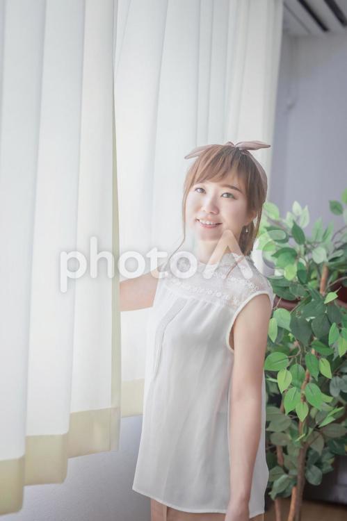 白いカーテンから差し込む朝日を浴びる若い女性 窓,朝日,換気の写真素材