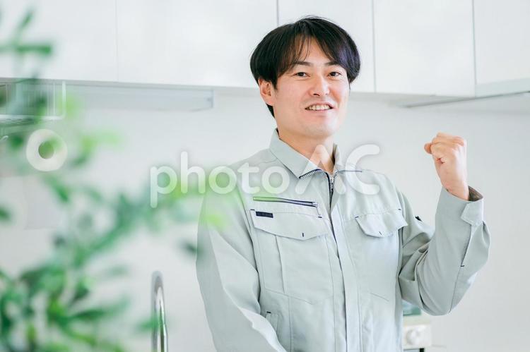 キッチンと作業着姿の男性（カメラ目線） 工務店,作業服,設備の写真素材