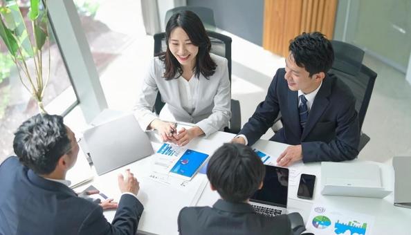 テーブルを囲んで会議するビジネスパーソンの写真