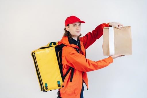 紙袋を見せるフードデリバリーの男性（白背景） 配達,フードデリバリー,デリバリーの写真素材