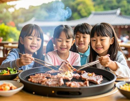 外で焼肉を楽しむ子供たち和やかなひととき 外で焼肉を楽しむ子供たち和やかなひとときの写真
