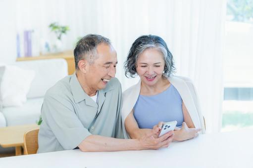 リビングでスマホを見るシニア夫婦 リビングでスマホを見るシニア夫婦 スマホ,笑顔,シニアの写真素材